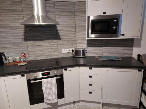a kitchen with white cabinets and a microwave at Flat 6 Corner House in Doncaster