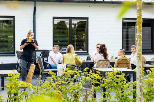 uma mulher em pé na frente de um grupo de pessoas sentadas às mesas em TOP Spa 2+2 em Voorthuizen
