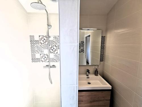 een witte badkamer met een douche en een wastafel bij L ancrage - proche de la plage in Brem-Sur-Mer