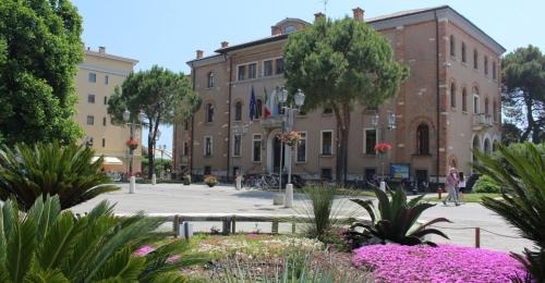a building with flowers in front of a courtyard at Comfort with terrace at Grado Pineta - Beahost in Grado-Pineta