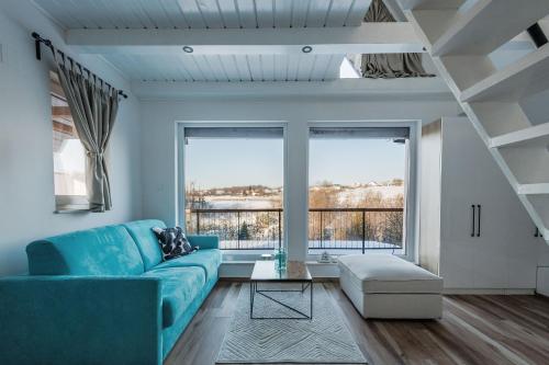 a living room with a blue couch and large windows at Franc Holiday House With a Spacious Terrace, Hot Tub And Sauna in Lopatinec