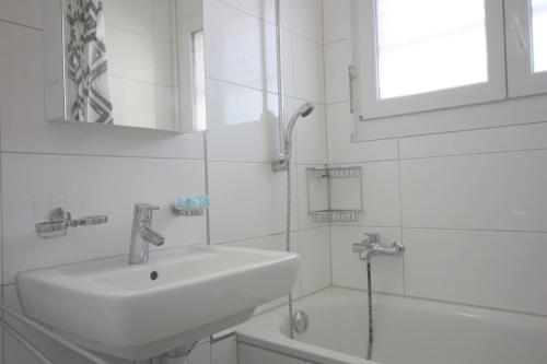 ein weißes Bad mit einem Waschbecken und einer Dusche in der Unterkunft Swiss Star District 11 - Self Check-In in Zürich