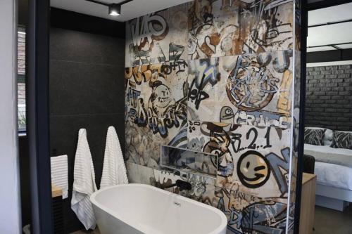 ein Bad mit einer mit Graffiti bedeckten Wand in der Unterkunft LoftHill in Welkom