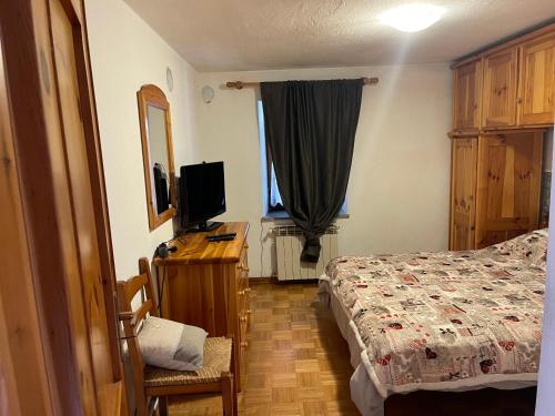 - une chambre avec un lit et un bureau avec une télévision dans l'établissement La casa di famiglia, à Brusson