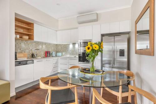 a kitchen with a glass table with a vase of flowers at Modern Twist + Old World Charm ~ 3Bed/2Bath/2Car in Brisbane