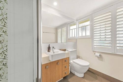 a white bathroom with a toilet and a sink at Modern Twist + Old World Charm ~ 3Bed/2Bath/2Car in Brisbane