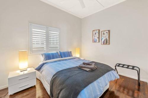 a white bedroom with a bed and a night stand at Modern Twist + Old World Charm ~ 3Bed/2Bath/2Car in Brisbane