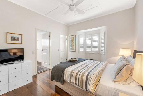 a white bedroom with a bed and a tv at Modern Twist + Old World Charm ~ 3Bed/2Bath/2Car in Brisbane