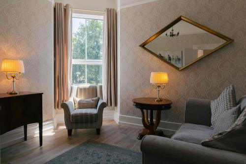 a living room with a couch and a chair and a mirror at Cranmere Lichfield in Lichfield