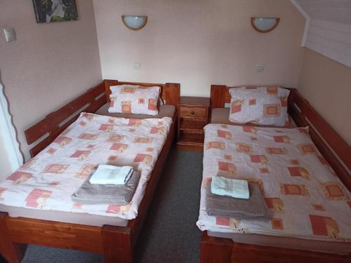 two twin beds in a room with two tables at Hotel Koloniál Skalité in Skalité