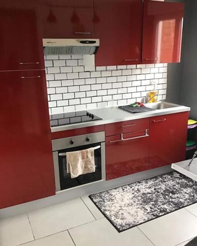 - une cuisine équipée de placards rouges, d'une cuisinière et d'un évier dans l'établissement Appt 56m2 en plein centre ville et mer a 200m, à Berck-sur-Mer