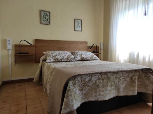 a bedroom with a bed with a blanket and a window at Casa Loli-Villar in Luarca