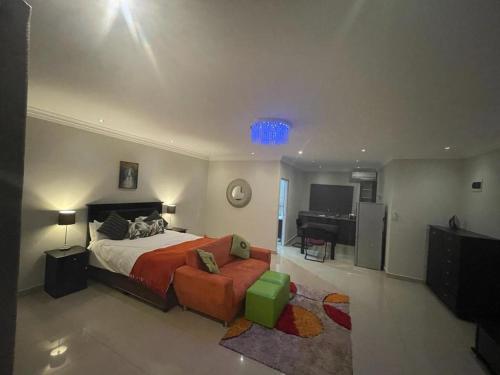 a bedroom with a bed and a couch and a desk at Illovo Beach house in Amanzimtoti