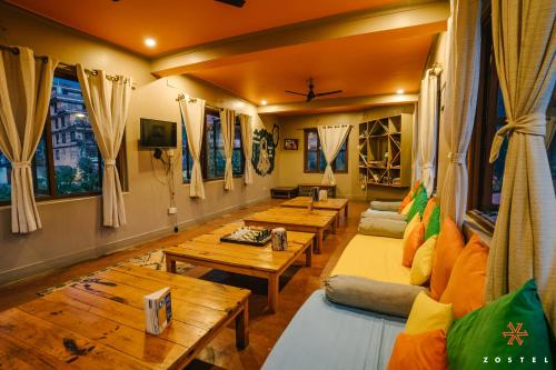 una sala de estar con sofás, mesas y ventanas en Zostel Pokhara, en Pokhara