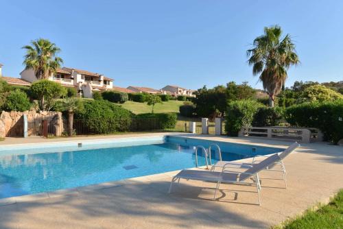 a swimming pool with two chairs next to a house at Résidence les Hameaux de Bocca del Oro in Porto-Vecchio