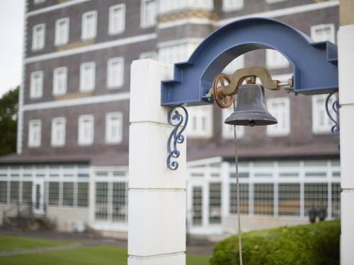 a bell hanging on a white fence in front of a building at Wellness Forest Nasu in Nasu