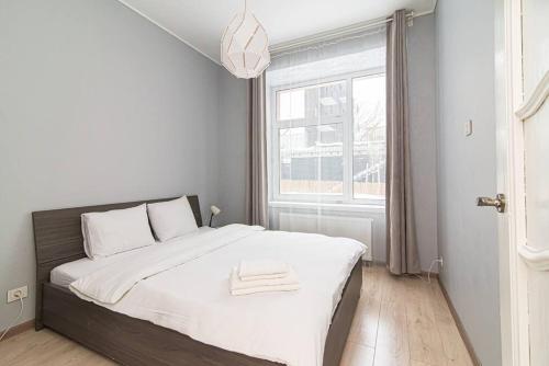 a bedroom with a bed with white sheets and a window at Spacious Apartment with Great Location/URBAN RENT in Vilnius