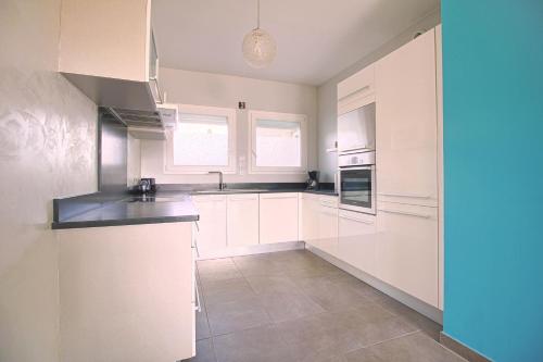 une cuisine blanche avec des armoires blanches et un évier dans l'établissement Appartement Roi Théodore Ajaccio, à Ajaccio