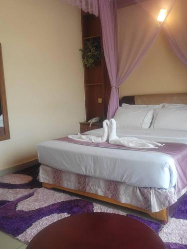 a bedroom with two beds and a purple rug at The Tick Hotel in Kampala
