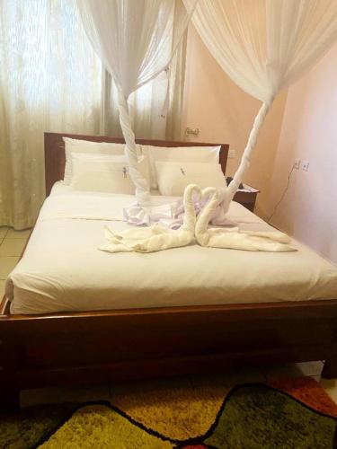 a bed with white sheets and white curtains at The Tick Hotel in Kampala
