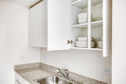 una cocina blanca con fregadero y armarios blancos en UES 2BR w DM Elevator Gym nr Central Park NYC-919, en Nueva York