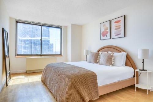 a white bedroom with a large bed and a window at UES 2BR w DM Elevator Gym nr Central Park NYC-919 in New York