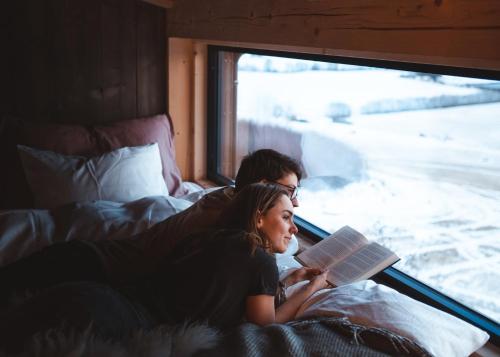 um homem e uma mulher deitados na cama a ler um livro em Fuglekassehytta 