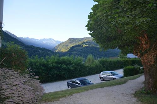 two cars parked in a parking lot with mountains in the background at Évasion Hébergement in Allevard