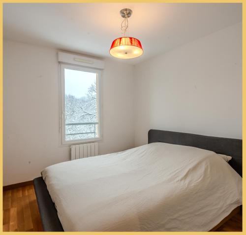 1 dormitorio con cama blanca y ventana en Appartement T2 Moderne St Julien, en Saint-Julien-en-Genevois