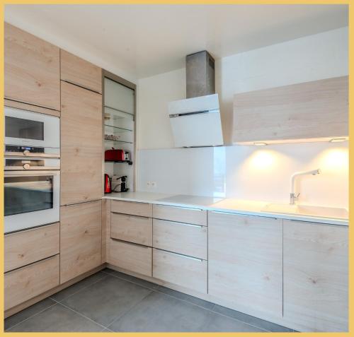 a kitchen with wooden cabinets and a sink at Appart T2 I Moderne I St Julien in Saint-Julien-en-Genevois