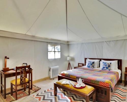 a bedroom with a bed and a desk in a room at The Heritage Luxurious Camp in Jaisalmer