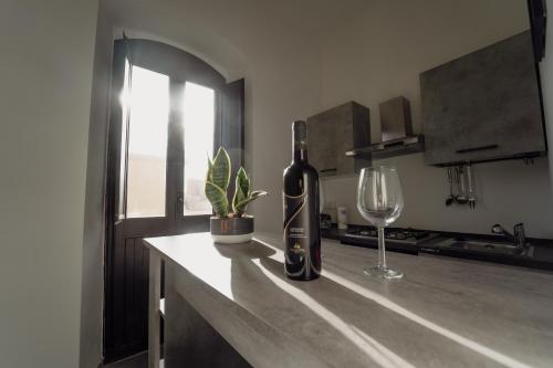 una botella de vino y una copa de vino en una barra en Casa Vacanze - Il Balconcino sul Castello, en Iglesias