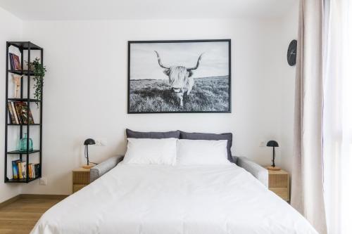 Un dormitorio con una cama blanca con un toro en la pared en Studio cosy classé 3* proche RER, en Rueil-Malmaison