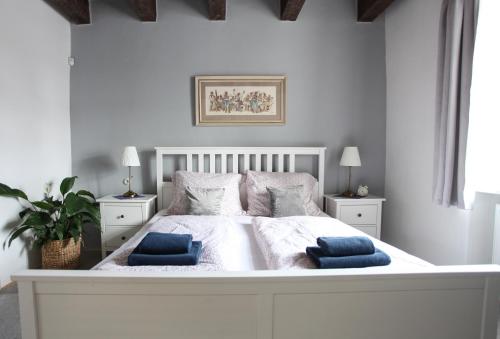 a white bedroom with a large white bed with blue pillows at Vinařský dům Mařatice in Uherské Hradiště