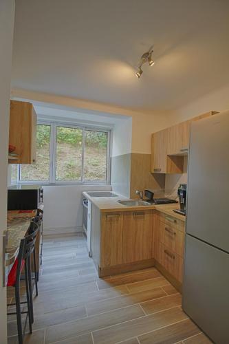 une cuisine avec des armoires en bois et un réfrigérateur blanc dans l'établissement Appartement Eugénie centre-ville Ajaccio, à Ajaccio