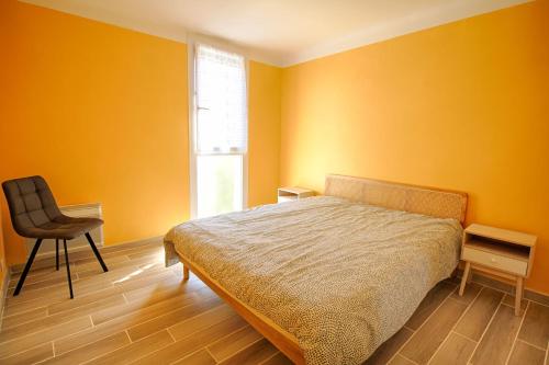 - une chambre avec des murs jaunes, un lit et une chaise dans l'établissement Appartement Eugénie centre-ville Ajaccio, à Ajaccio
