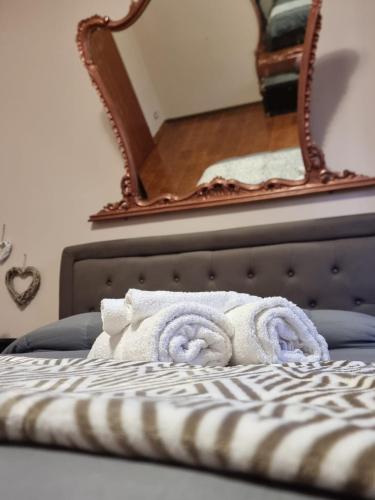 a pile of towels on a bed with a mirror at VintageCo. Apartments in Motta SantʼAnastasia