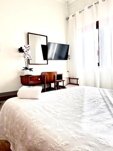 a white bedroom with a bed and a desk at Residencial Moderna in Torres Vedras