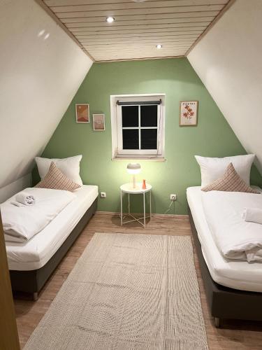 2 Betten in einem Zimmer mit grüner Wand in der Unterkunft Lilly's Häuschen in Obereisenheim