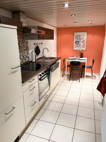 a kitchen with orange walls and a table with chairs at Lilly's Häuschen in Obereisenheim