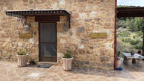 a stone building with a door and two potted plants at STONEHOUSE & CASA AL SOLE e AL MARE in Nea Roda