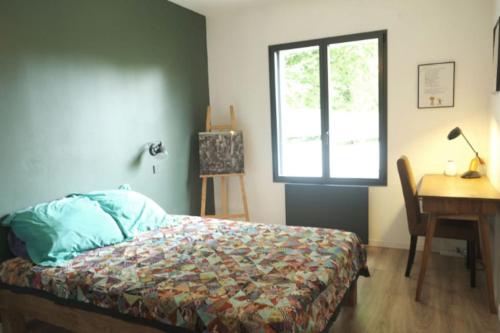 a bedroom with a bed and a desk and a window at Maison d'architecte pour les JO in Saint-Hilarion
