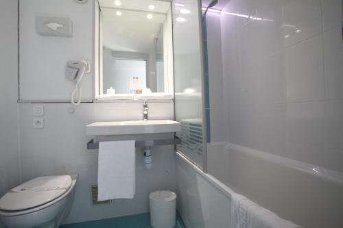 a bathroom with a sink and a toilet and a mirror at Kyriad Nancy Sud - Ludres in Ludres