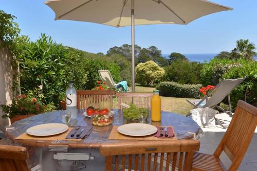 a table with plates of food and an umbrella at Résidence les Hameaux de Bocca del Oro in Porto-Vecchio