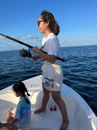 a woman standing on a boat with a child holding a fishing pole at Wish Guesthouse in Huraa
