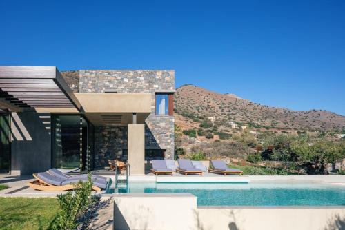 a house with a swimming pool with lounge chairs next to it at Villa Katy in Agios Nikolaos