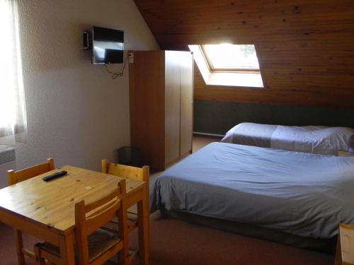 a room with two beds and a table and a window at Hôtel Résidence Les Colchiques in Le Monêtier-les-Bains