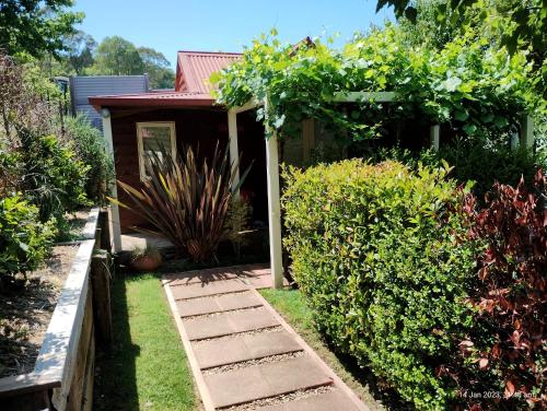 un jardin avec un chemin menant à un hangar dans l'établissement Bella Rouge Cottage, à Bright