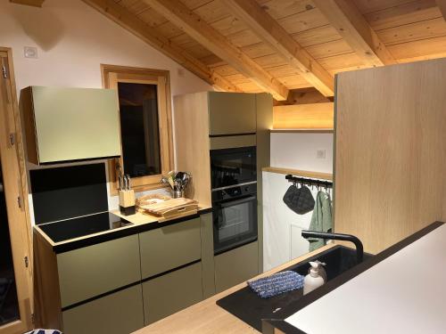 a kitchen with black appliances and wooden ceilings at Chalet La Tarine in Saint-Marcel