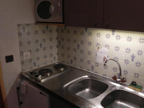 a kitchen with a sink and a stove at Hôtel Résidence Les Colchiques in Le Monêtier-les-Bains